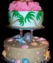 Hawaiian Beach Birthday Cake. Brown and blue buttercream iced, round 2 tiers decorated with seashells, pearls, starfish, palm trees and topped with Hawaiian flowers. Everything on this cake is edible. (Serves 28-55 party slices.) 